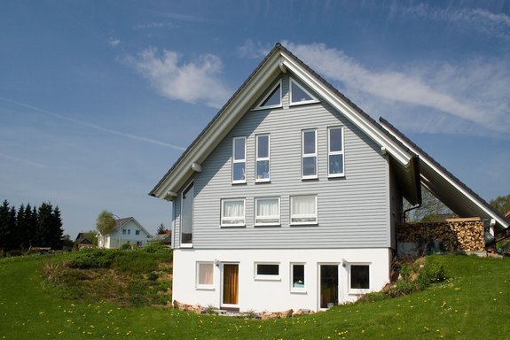 Satteldachhaus mit grauer Holzfassade in Hanglage