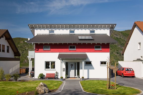 Holzhaus mit versetztem Pultdach und roten Akzent