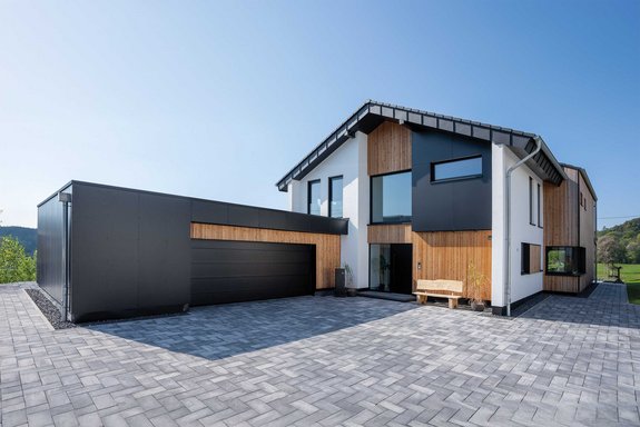 Moderne Holz-Putz-Fassade mit kontrastreichem Satteldach und Flachdach-Garage