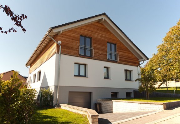 Aufstockung mit Satteldach und Holzverkleidung im Obergeschoss
